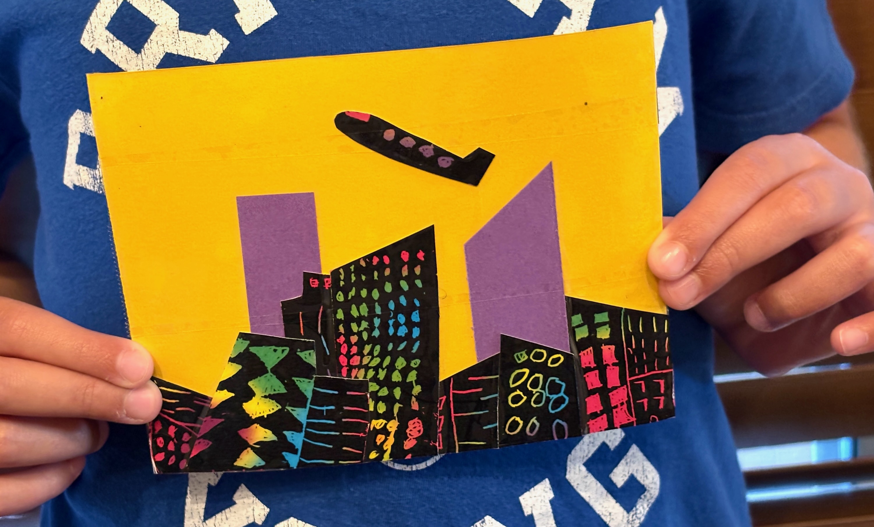 Amy's scratch-art city skyline craft with a paper airplane flying over it